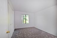 A room with a carpeted floor and a window with bars on it.