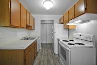 A kitchen with white appliances and wooden cabinets.