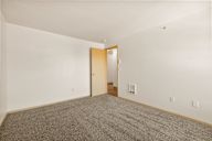 a living room with carpet and a door to a hallway