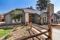 the front of a house with a yard and a wooden fence