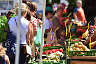 people buying fruits and vegetables at an outdoor market