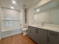 A white bathroom with a wooden floor and a white tub.