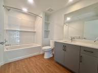A white bathroom with a wooden floor and a white toilet.