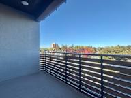 A balcony with a black railing overlooks a cityscape.