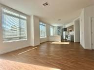 A spacious room with wooden flooring and large windows.