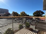 A parking lot with a metal fence in the foreground and a clear blue sky above.