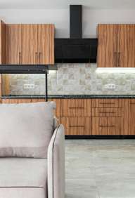 A modern kitchen with wooden cabinets and a black range hood.