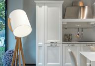 A white lamp stands next to a white cabinet in a kitchen.