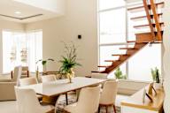 A dining room with a wooden table and white chairs.