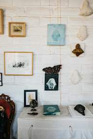 A white brick wall with a variety of objects including a globe, books, and framed pictures.