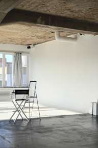 A chair with a laptop on it is in a room with a window.
