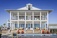 A white house with a pool in front.