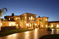 a mansion is lit up at night with a courtyard