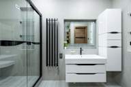 A modern bathroom with a white sink and a glass shower.