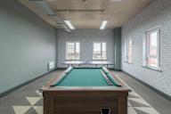 a large room with a pool table and two windows