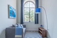 a living room with a couch and a blue lamp and a window