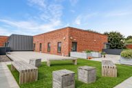 an outdoor area with wooden benches and a brick building