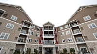 Apartment building with a central entrance and balconies on each floor.