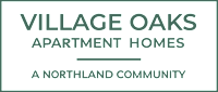 A sign that says "Village Oaks Apartment Homes" in white text on a green background.