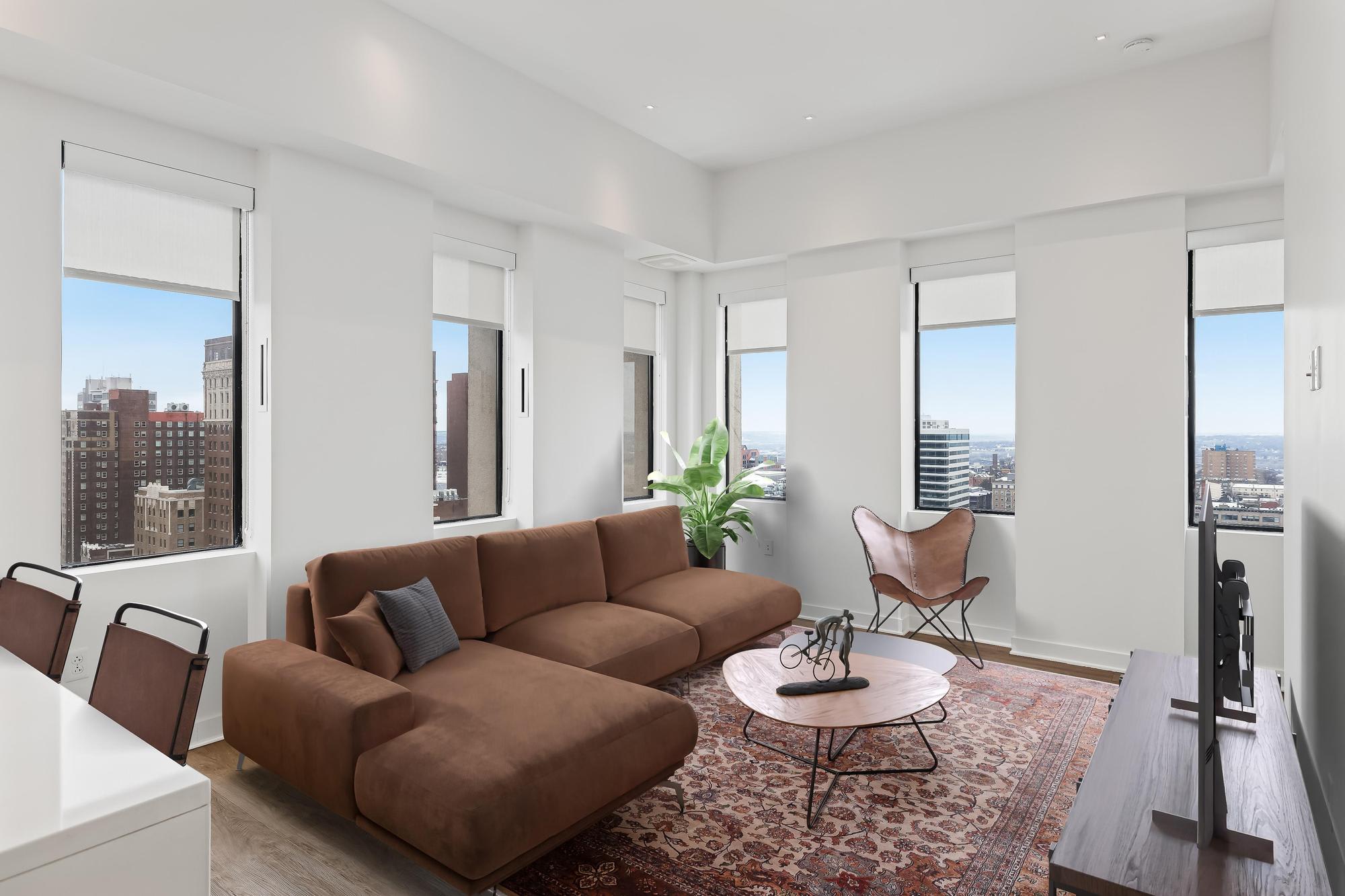 Living room at Sky on Main with a brown sofa, accent chairs, and a white coffee table