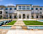 A white building with a pool in front of it.