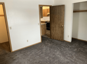 a bedroom with a door to a kitchen and a carpeted floor