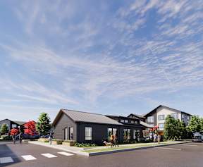 A modern building with a grey roof and a parking lot in front.