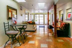 A hallway with a tiled floor and a table with chairs.