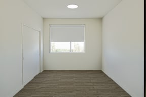 A room with a window and a carpeted floor.