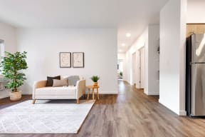 a living room with a couch and a rug and a kitchen with a refrigerator