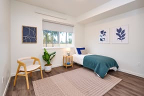 a bedroom with a bed and a chair and a window