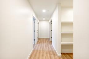 A long hallway with white walls and wood flooring.
