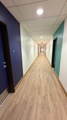 A long hallway with wood floors and doors on both sides.