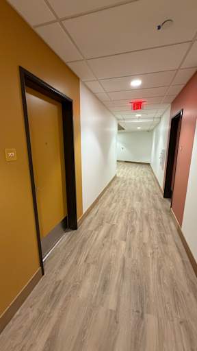 A long hallway with a red exit sign on the ceiling.