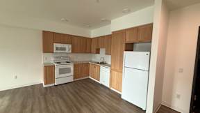 A kitchen with white appliances and wooden cabinets.
