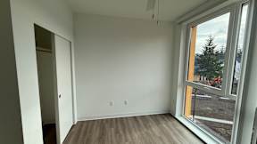 A room with a large window and wooden flooring.