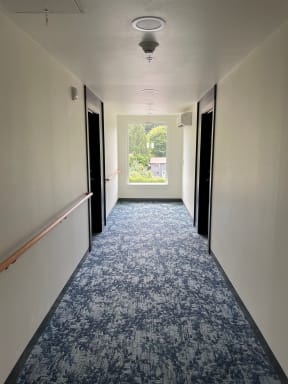 an empty hallway with white walls and blue carpet