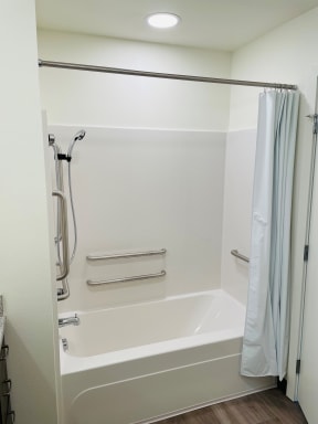 a small white bathtub with a shower curtain in a 555 waverly unit