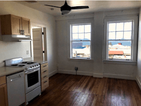 A kitchen with a stove top oven and a window overlooking a body of water.