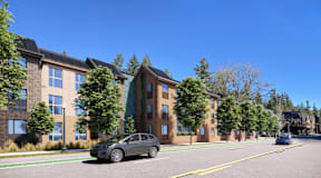 A grey car is parked on the side of a street in front of a building.