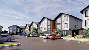 A row of modern townhouses with cars parked in front.