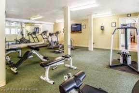A gym with a variety of equipment including treadmills, weights, and exercise machines.
