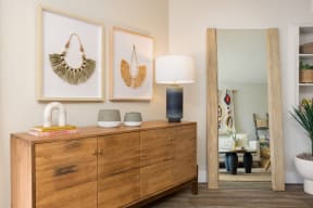 a living room with a dresser and three wall hangings