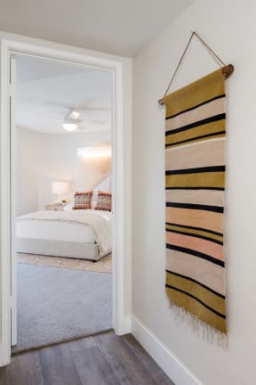 a bedroom with white walls and a white bed with a yellow and black blanket hanging on the