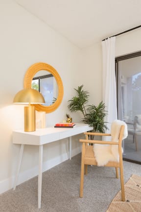 a white desk with a gold lamp and a chair in a room with a sliding glass door
