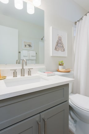 a small bathroom with a gray vanity and a white shower curtain