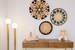 a wooden dresser with three woven wall art on the wall above it