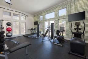 the gym has plenty of exercise equipment and windows