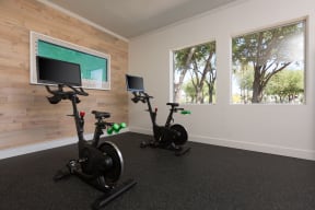 a home gym with two exercise bikes and a tv