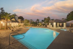 a swimming pool with chairs and umbrellas in front of a resort pool